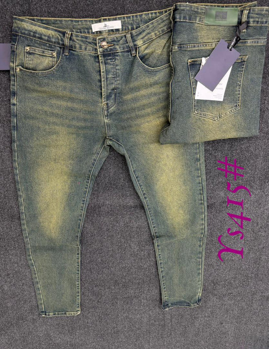 Pair of green jeans with tags on a gray surface